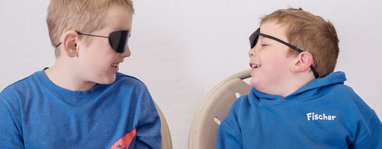 Two young boys wearing eye patches at a vision therapy session